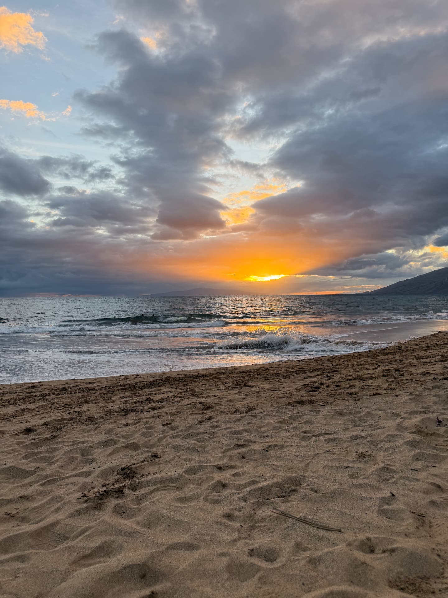 A golden Maui sunset over the shoreline with soft clouds